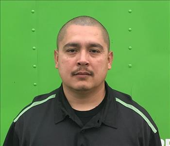 Man in black shirt in front of green background