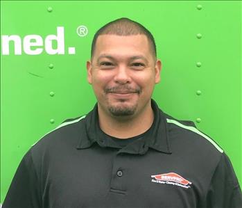 Man in black shirt in front of green background